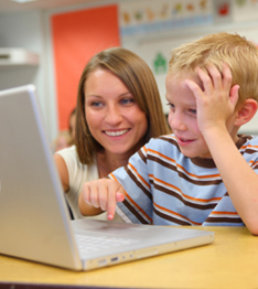 Teacher helps a student using a laptop